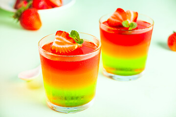 Glasses of tasty summer dessert layered colorful jelly with fresh strawberries