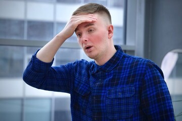 Young handsome ill sick man worker at office is suffering from heat, high temperature, headache and...