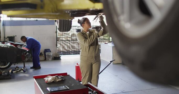 Video of biracial female car mechanic repairing car