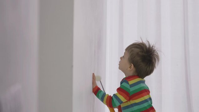 Funny toddler looking to paint the upper part of the wall