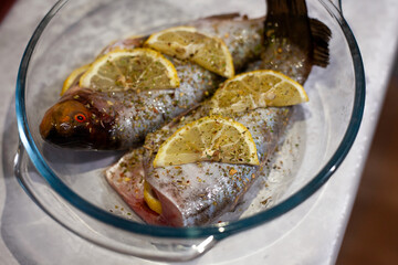 Raw fish with lemon in a glass bowl. Preparing for baking