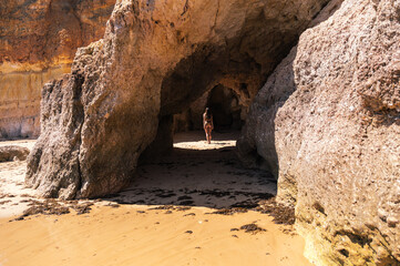 Carefree woman standing in cave on sandy beach