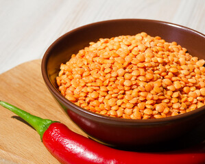 Lentils in a bowl and with red pepper on the board.