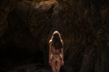 Woman in bikini standing near rock at seaside