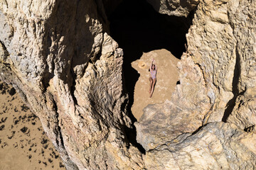 Woman lying in hole in stone formation