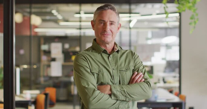 Portrait of happy caucasian businessman looking at camera at office