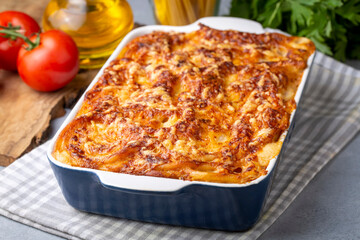 Pasta casserole bechamel sauce topped with melted mozzarella cheese and served in a white baking dish on a table (Turkish name; firinda makarna or firin makarna)