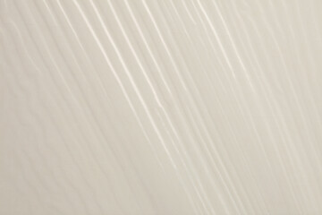 Empty crumpled wet cellophane paper blank texture copy space wave background. Beige pastel color.