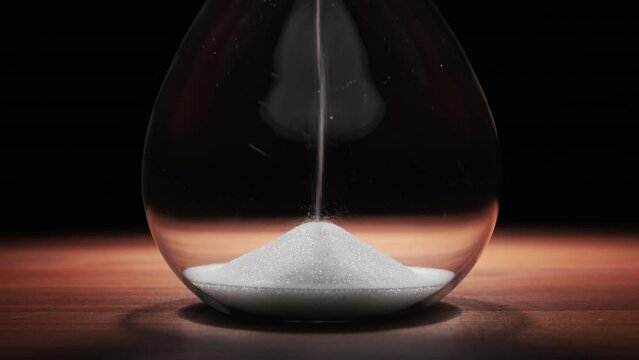 シンプルな黒色の背景に静かに時間の流れを計測する砂時計