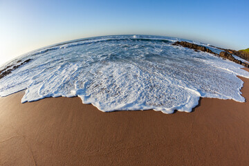 Beach sand ocean sea wave wash close up wide angle photo in morning light of nature's coastline detail.