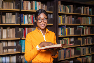 Young female student read and learns by the book shelf at the library.Reading a book.