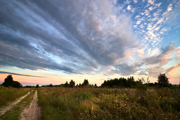 Scenic countryside landscape with rural dirt road at sunrise. Summer landscape.