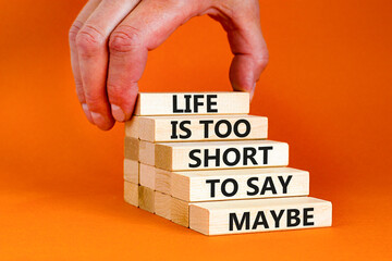 Life is short for maybe symbol. Concept words Life is too short to say maybe on wooden blocks on a beautiful orange table orange background. Businessman hand. Business motivational life maybe concept.