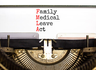 FMLA family medical leave act symbol. Concept words FMLA family medical leave act typed on beautiful old retro typewriter. Businessman hand. Medical FMLA family medical leave act concept.
