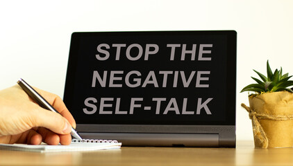 Stop negative self-talk symbol. Concept words Stop the negative self-talk on the black tablet. Businessman hand with pen. Psychological and stop negative self-talk concept. Copy space.