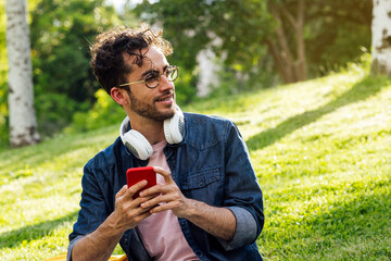 Outdoor portrait of handsome young hipster man with mobile phone.