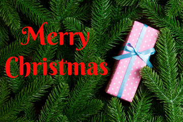 Merry Christmas text. Top view of Christmas gift box on fir tree background. Time for holiday concept with copy space