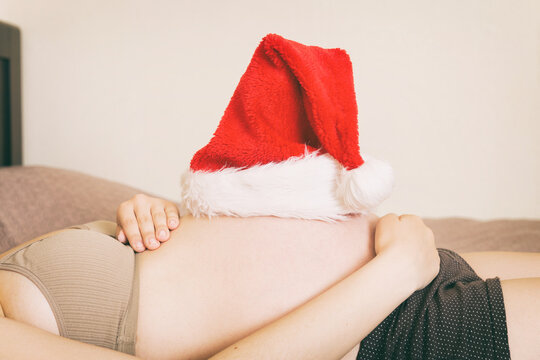 Pregnant in santa hat holding her belly. Christmas and New year concept
