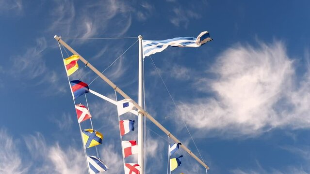 Sea ship flags on a mast waving in the wind against sunny blue sky. International maritime signal flags. Marine garland	