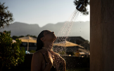 Girl takes a shower at sunset
