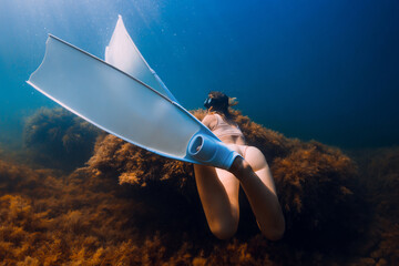 Woman with diving mask and freedive fins posing underwater on the deep. Freediving in blue ocean