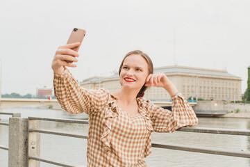 Beautiful woman taking a selfie on the embankment