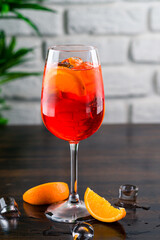 Shining cocktail Aperol syringe in a wine glass with ice and a slice of orange on a dark background
