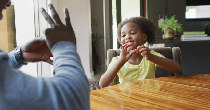 Vertical video of african american father and daughter using sign language