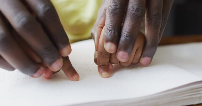 Vertical video of african american father and daughter reading braille alphabet