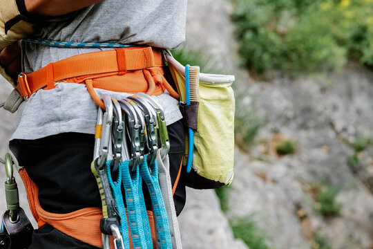 Faceless mountaineer holding climbing equipment in forest