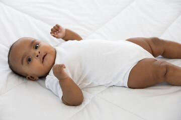 cute African baby lying on bed at home