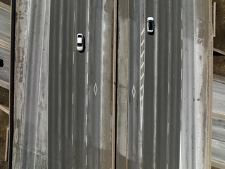 HOV lane logos are seen on a large highway interstate as two cars pass by.