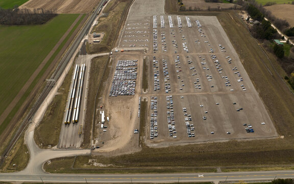 A Drone View Beside An Auto Distribution And Homologation Center. Autotrack Train Cars Sit Beside The Large Center, Next To A Railway.