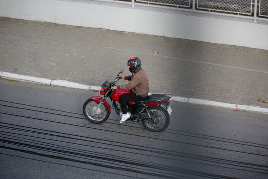 Motoqueiro na estrada em movimento com moto vermelha.