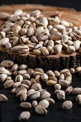 fried salty pistachio snacks are laid out on a wooden substrate on a dark background close-up