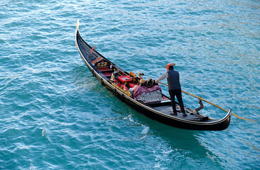 Fototapeta na wymiar Venetian gondolier carries tourists on gondola in Grand Canal in Venice, Italy