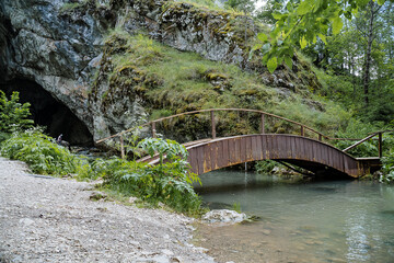 The ancient rock entrance to the cave is a wooden bridge over the river, outdoor recreation,...