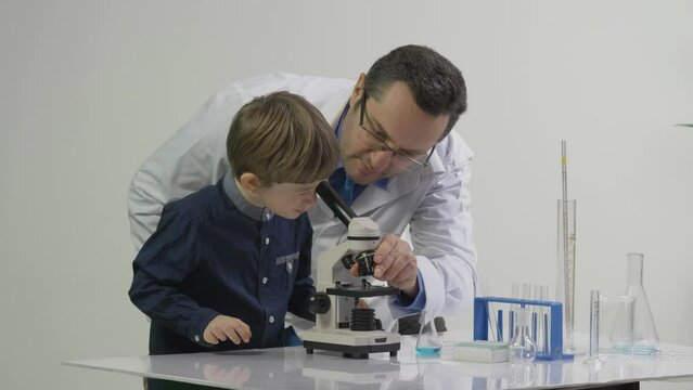 Teacher learning the little student to use chemical laboratory microscope