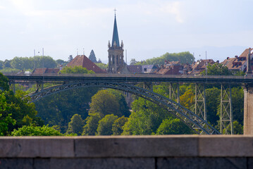 Church tower of Minster at the old town of Bern on a blue cloudy summer day with Kornhaus Bridge in the foreground. Photo taken June 16th, 2022, Bern, Switzerland.