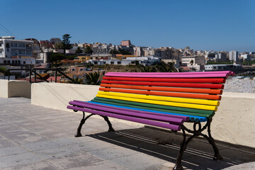 Wooden street bench painted in the colours of the rainbow and the LGBTQ flag, Pride Day concept