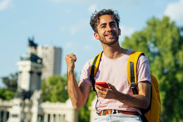 Outdoor portrait of handsome euphoric young man with mobile phone.