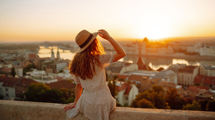 Young female tourist enjoys the view of the city at sunset. back view.  Lifestyle, travel, tourism,...