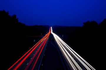 A shot of cars on both sides of the carriageway disappearing over the horizon - obrazy, fototapety, plakaty
