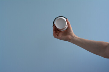 White paper cup of coffee in hand. Isolated. On blue background