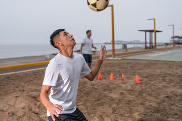 Man catching a ball with his chest while training footvolley on a beach