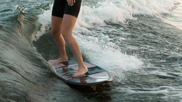 A female surfer jumping on a wakeboard. An experienced wakeboarder splashes water drops into the camera.