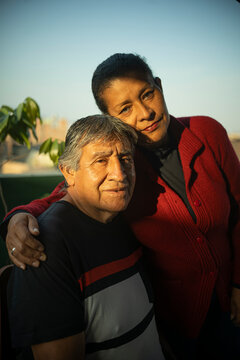 Retrato de padres de familia latina posando en su hogar durante el atardecer 
