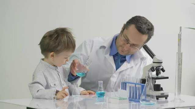 Little kid learning from his father the chemistry in the laboratory