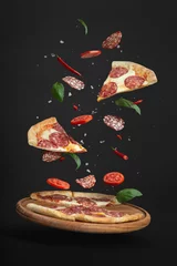 Plexiglas foto achterwand flying pizza with ingredients on a black background © Berzyk