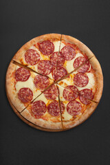 Pepperoni pizza on wooden board and black background